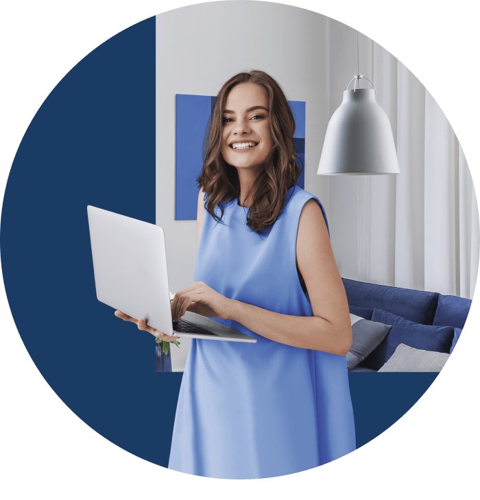 Mulher jovem está na sala de casa com vestido azul. Ela sorri enquanto segura um notebook, representando TIM Internet.