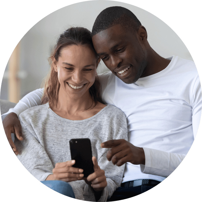 Mulher e homem sorriem enquanto olham para o celular que está mãos da mulher, representando o plano TIM Internet Rural.